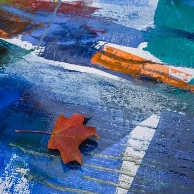 Detail of a leaf resting on a blue painting